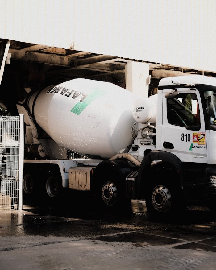 White cement mixer truck at construction site, ready for transportation.